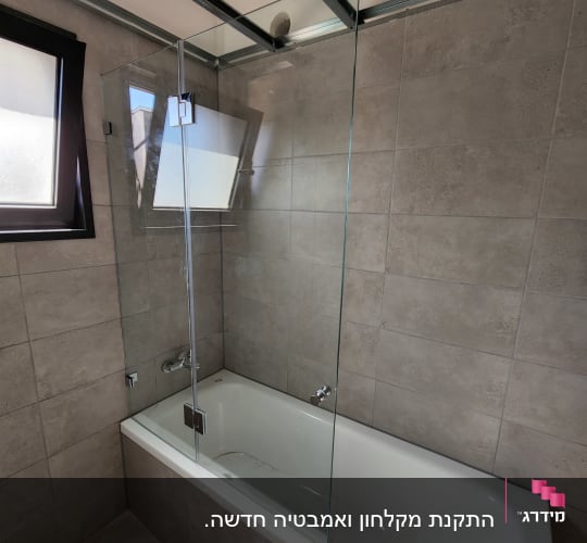 bathtub with glass shower screen and tiled walls